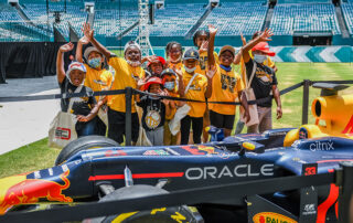 Image for a press release - kids pose with a Formula 1 car at the Formula 1 Miami Grand Prix Watch Party